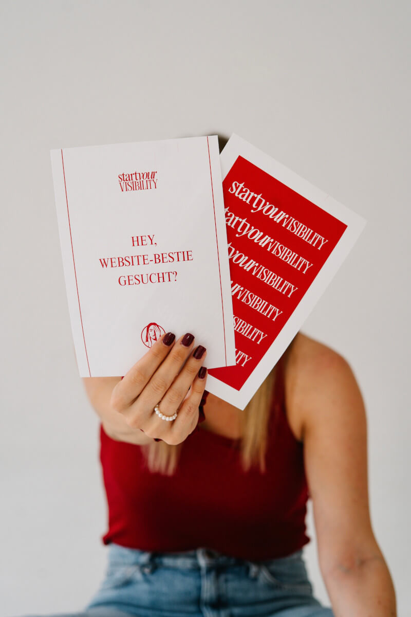 Jennifer sitzt am Boden und hält Schild ‚Website-Bestie gesucht?‘ - Strategisches Webdesign für selbstständige Frauen